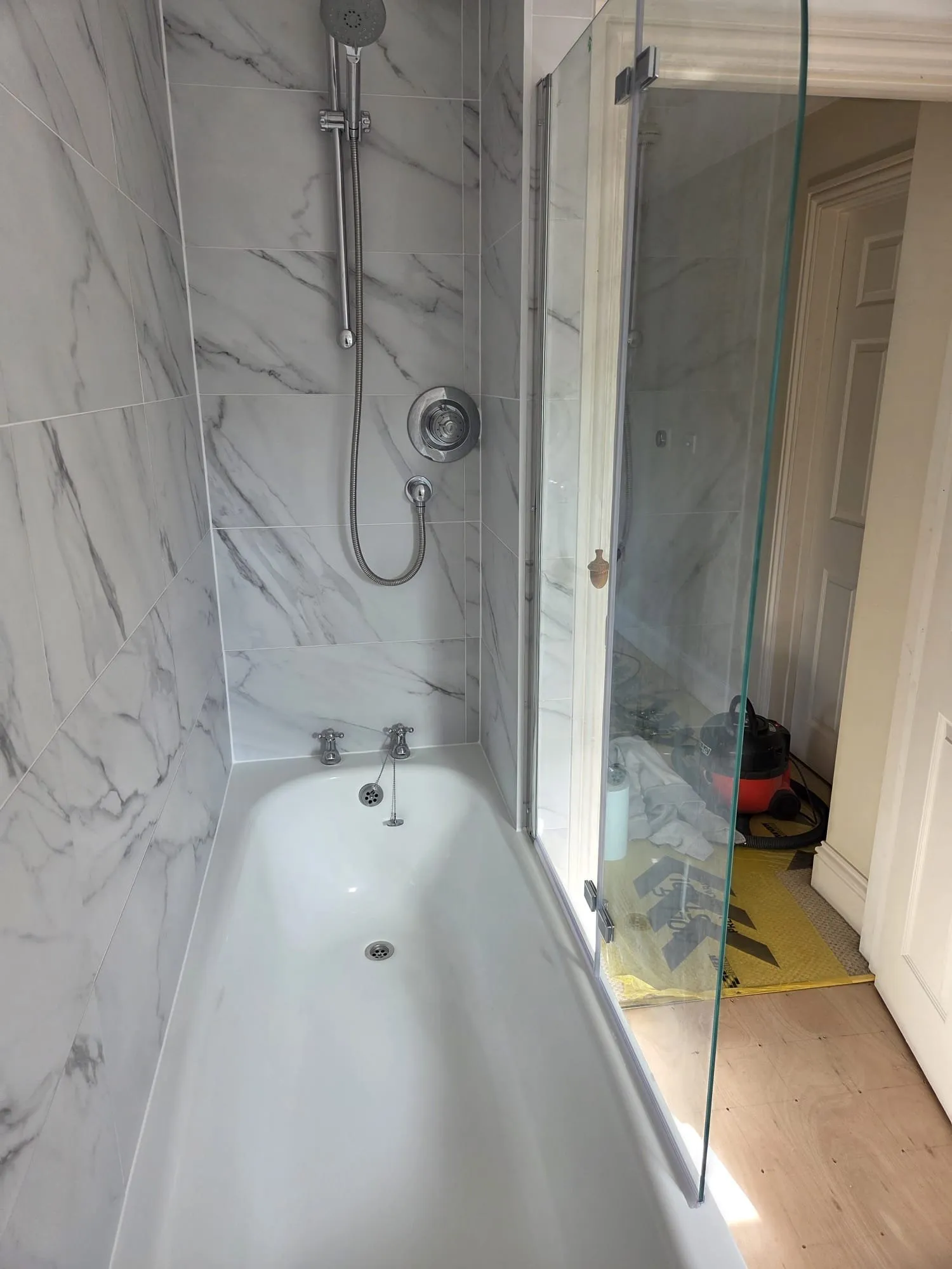New bath with shower over and marble-effect tiling in a Petersfield bathroom renovation